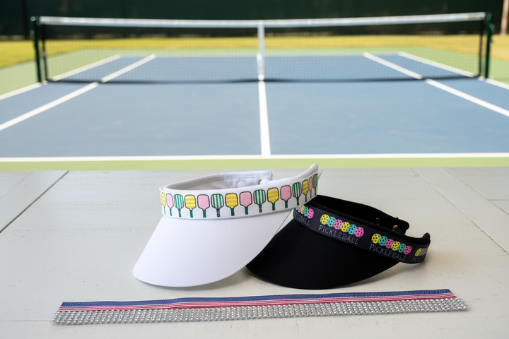Visors with shorter bands on table in front of pickleball court